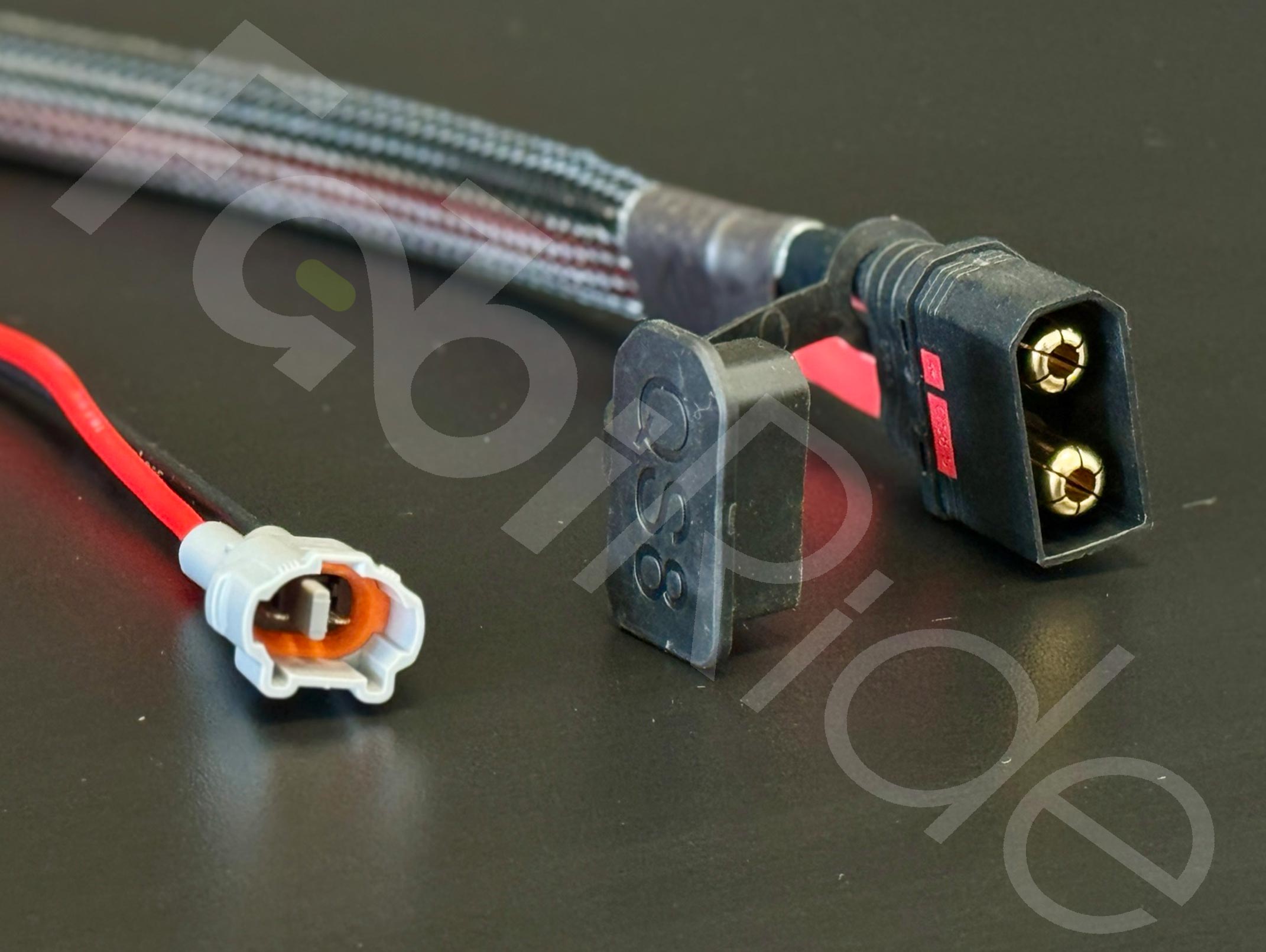 Iš arti nufotografuoti automobilių laidai su 2 kontaktų jungtimi ir apsaugotu SAE maitinimo kištuku su dangteliu.